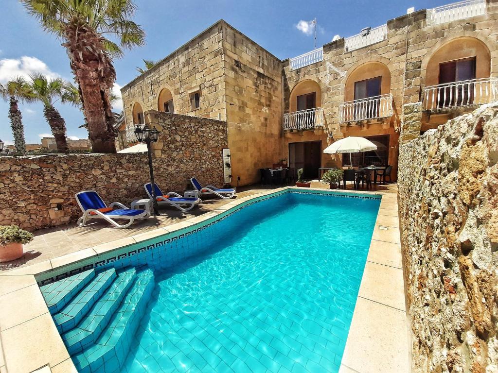 basen przed budynkiem z palmami w obiekcie Blossom Farmhouses w mieście Għasri