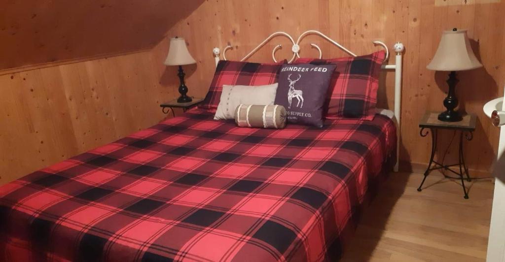 a red and black plaid bed in a room at Les Gites Makadan in Normandin