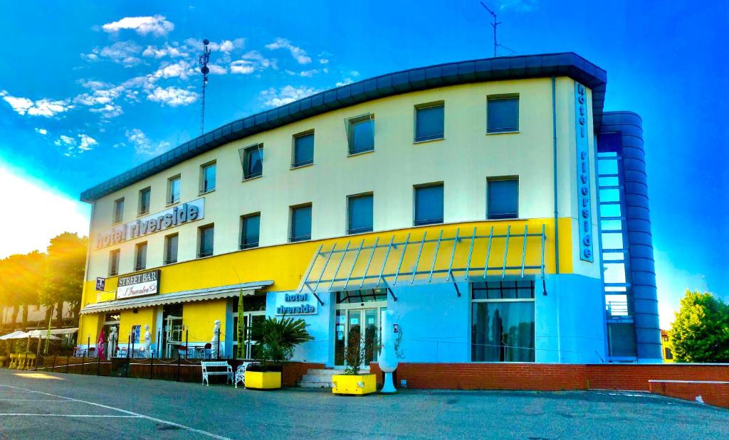 un edificio amarillo y azul con una persona de pie delante en Hotel Riverside, en Módena