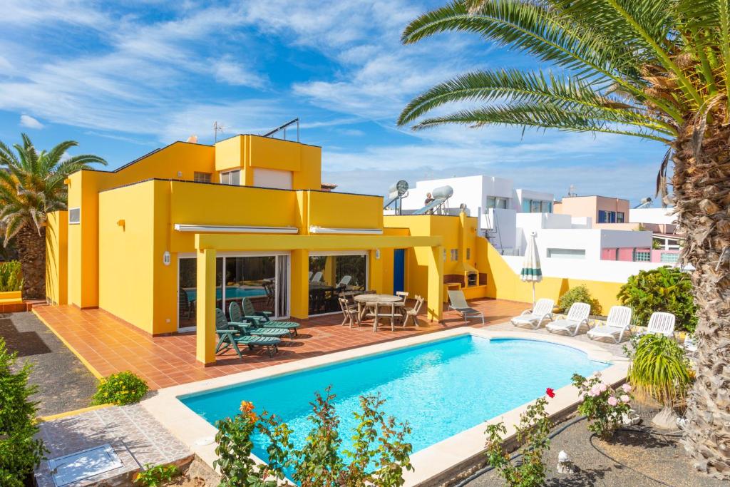 a villa with a swimming pool in front of a house at Villa Mariposas in Corralejo