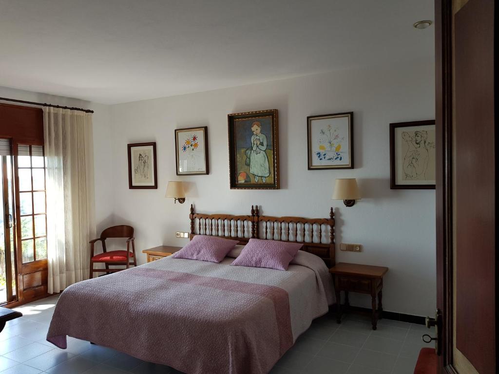 1 dormitorio con 1 cama y algunas fotos en la pared en Hostal Sa Barraca - Adults Only, en Begur