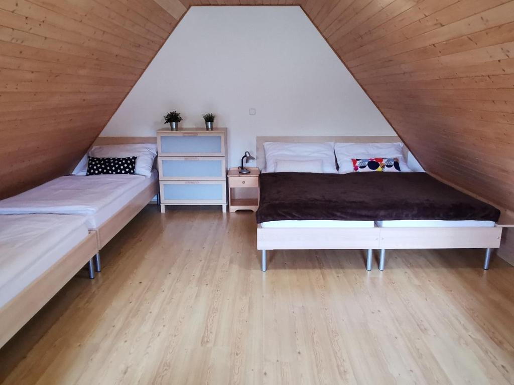 a attic bedroom with two beds and wooden floors at Apartmány Dolní Moravice in Dolní Moravice