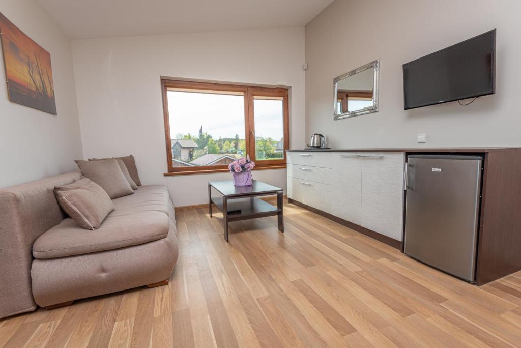 a living room with a couch and a tv at Paukščių Tako Svečių Namai in Šventoji