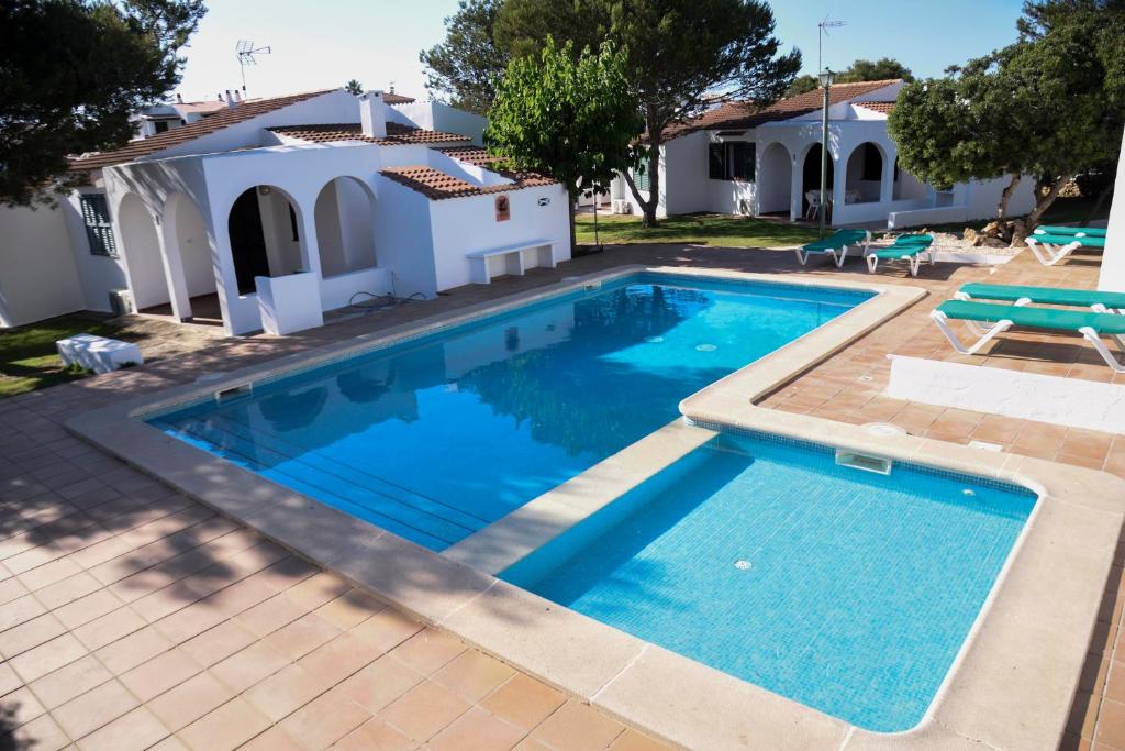 a swimming pool in front of a house at Villas Las Alondras in Cala en Forcat