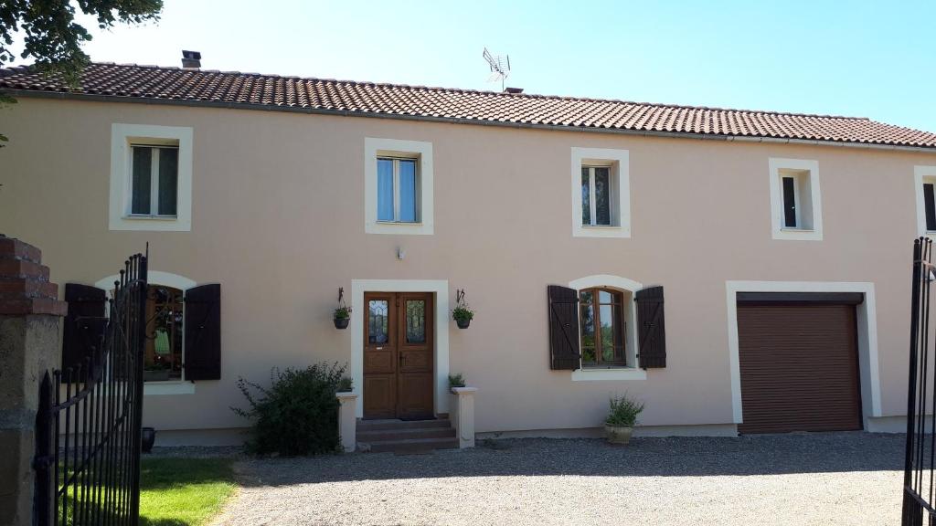 Casa blanca con puerta y ventanas marrones en Jazz et Vacances, en Monlezun