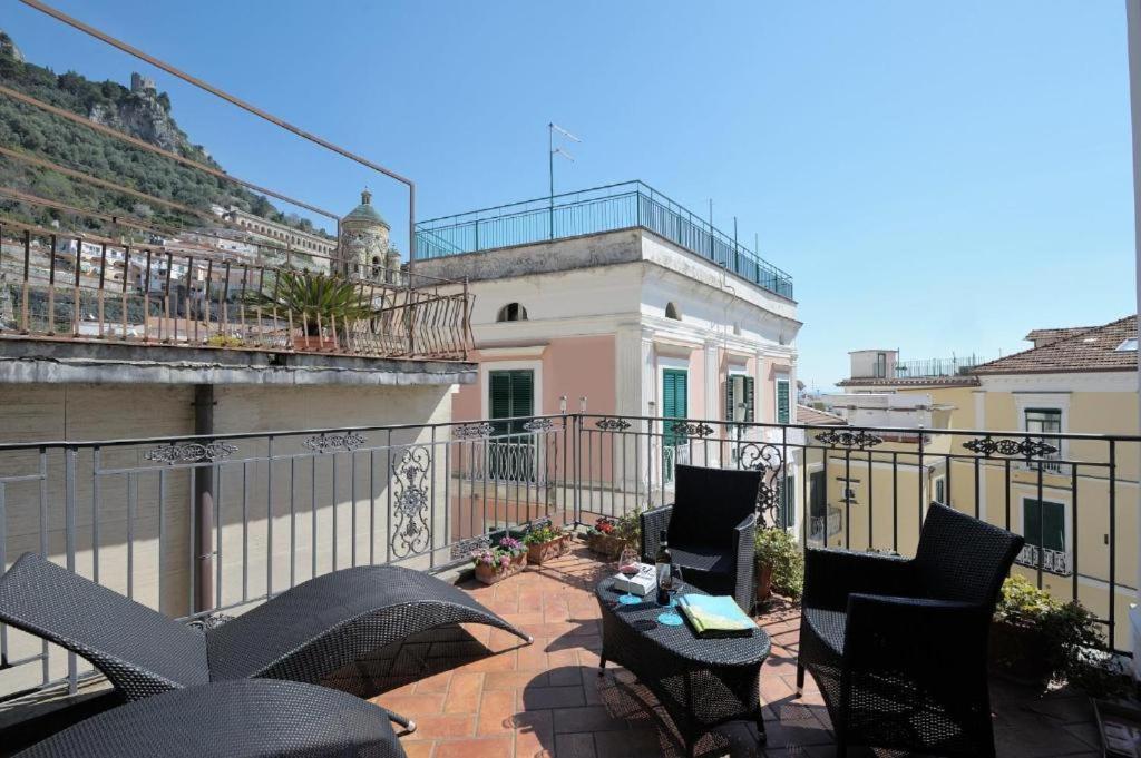 a balcony with chairs and an umbrella on a building at Residenza Del Duca Rooms & Apartments in Amalfi