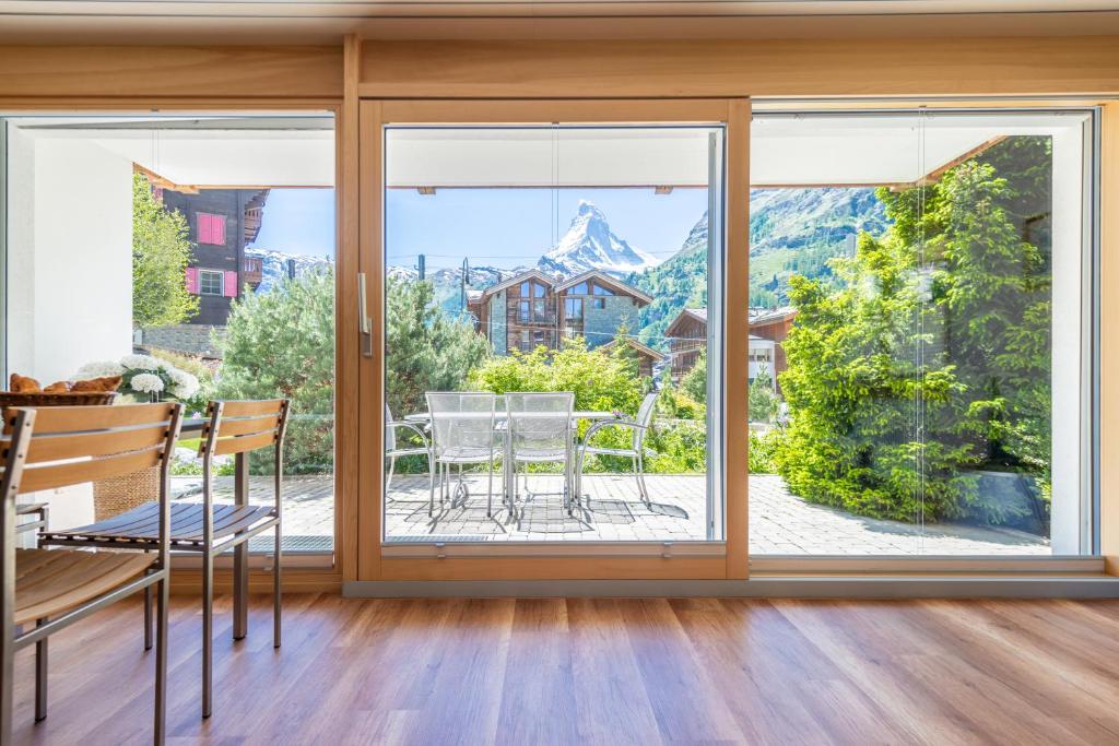 una sala da pranzo con finestre, tavolo e sedie di Haus Alpine a Zermatt