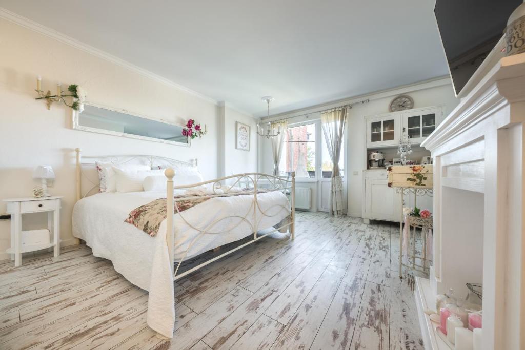 a bedroom with a white bed and a wooden floor at Vintage Lounge studio by the sea in Liepaja in Liepāja