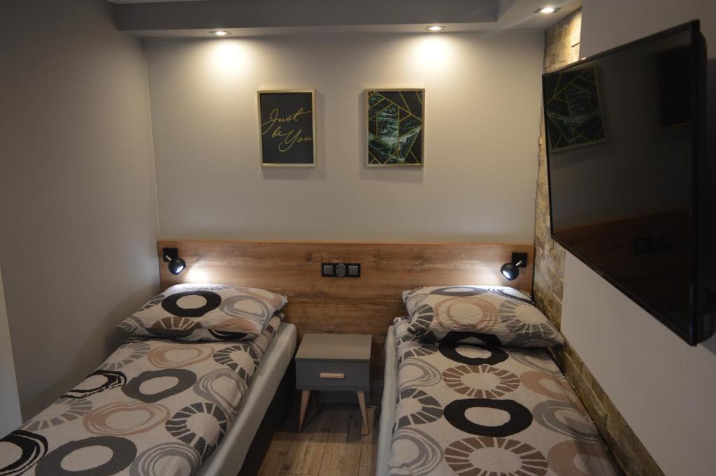 a small room with two beds and a tv at Zacisze in Rozalin