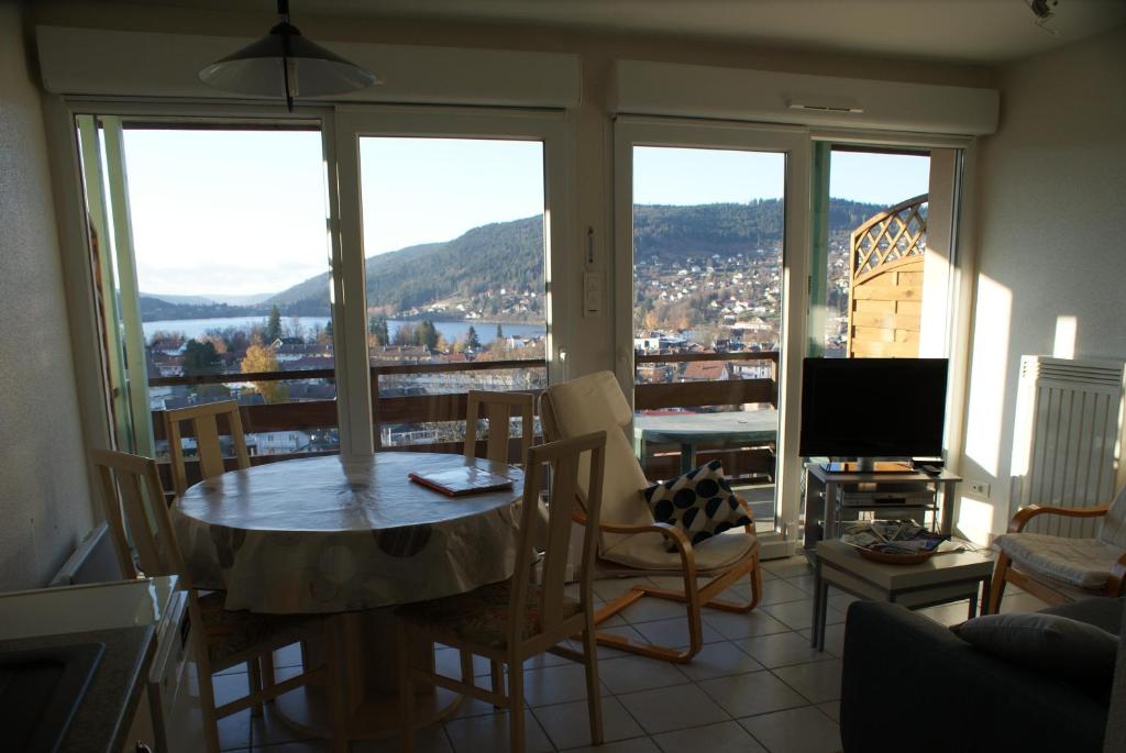 un salon avec une table, des chaises et une télévision dans l'établissement Les Charmilles, à Gérardmer