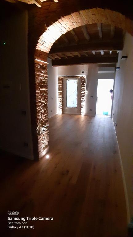 pusty pokój z drewnianą podłogą i ceglaną ścianą w obiekcie Il paradiso sopra le nuvole w mieście Peccioli