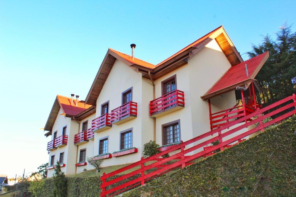 une maison avec balustrade rouge au sommet d'une colline dans l'établissement Pousada AlpenRose, à Campos do Jordão