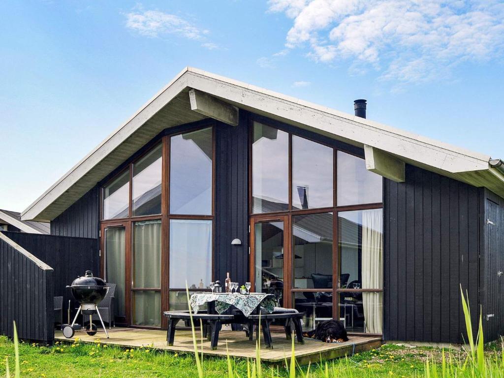 Thorsminde的住宿－8 person holiday home in Ulfborg，一间黑色房子,设有玻璃窗和桌子