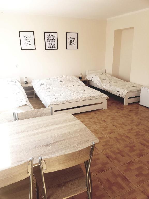 three beds in a room with wooden floors at Emides in Pobierowo