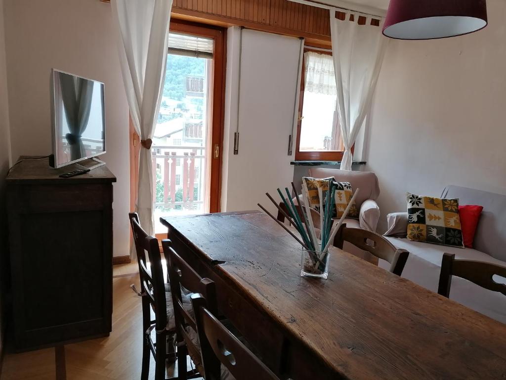 a dining room with a wooden table with chairs and a television at Courma House in Courmayeur