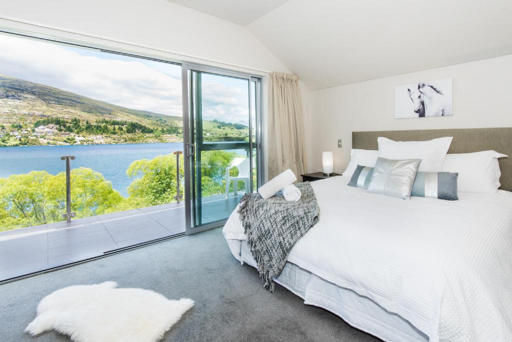 a bedroom with a large bed and a large window at Lakeside Luxury with Spa in Queenstown