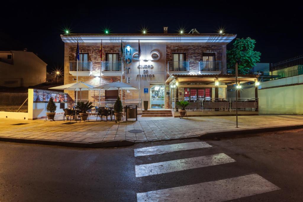a building with a table and chairs in front of it at night at Hotel Ciudad de Martos in Martos
