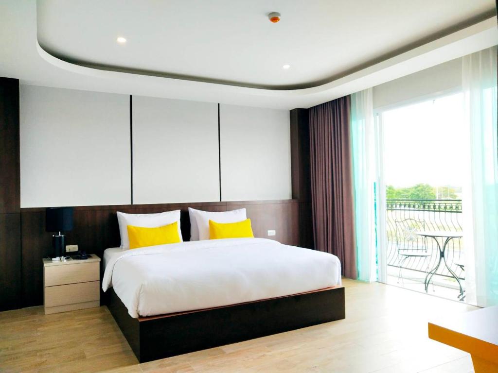 um quarto com uma cama grande e almofadas amarelas em โคโค่ โฮเทล KOCO Hotel em Nakhon Ratchasima