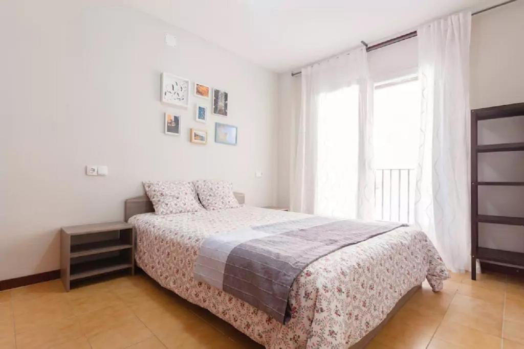 a white bedroom with a bed and a window at Flat near Lloret De Mar center and beach in Lloret de Mar