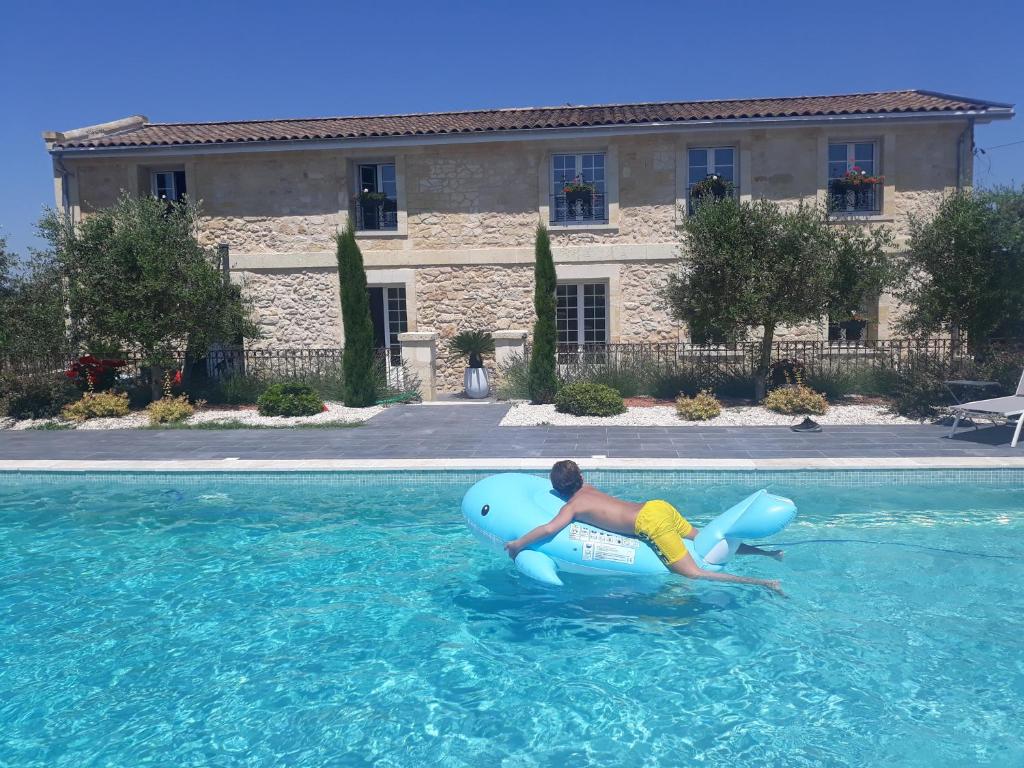 un niño está montando en una balsa en una piscina en DOMAINE DE GUILLEMIN en Saint-Louis-de-Montferrand