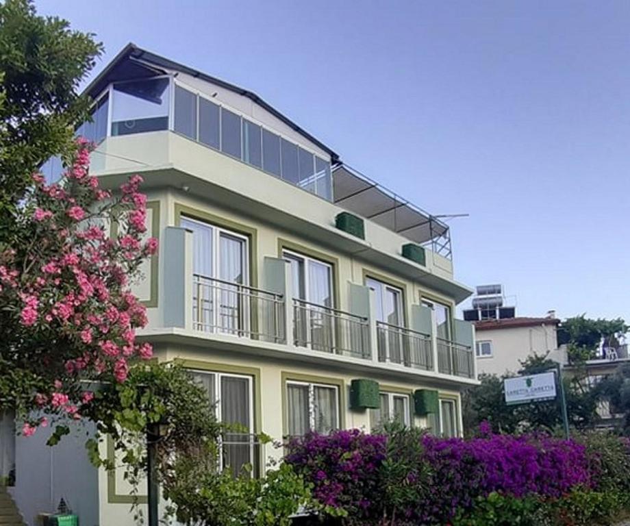 a large yellow building with balconies and flowers at Caretta Caretta Hotel in Dalyan