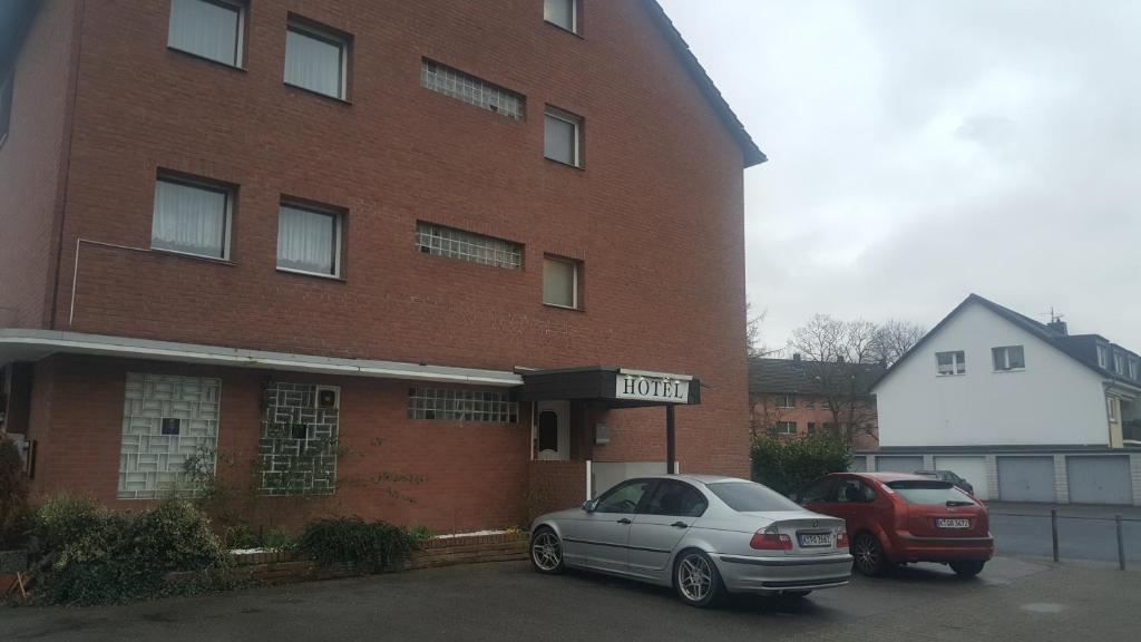 dos coches estacionados frente a un edificio de ladrillo en Hotel Heideklause en Colonia