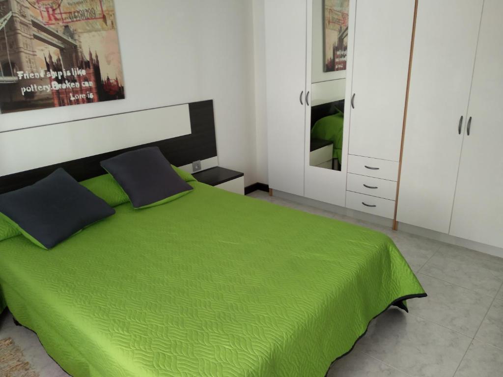 um quarto com uma cama verde e armários brancos em VUT "O Pazo" Sanxenxo os espera em Sanxenxo