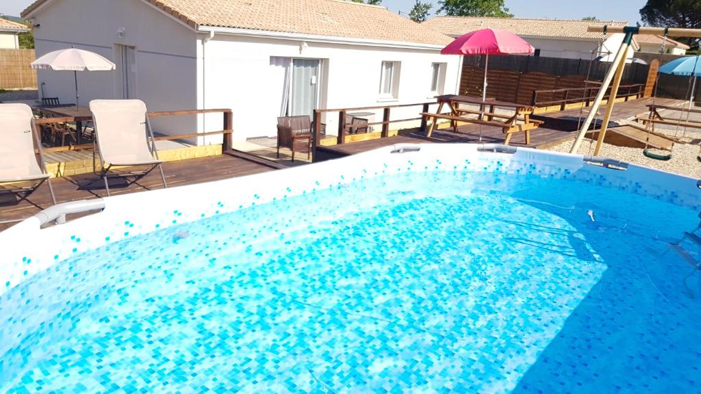 a large blue swimming pool with chairs and umbrellas at Bienvenue à Bordeaux! Parking Pétanque Wi Fi in Beychac-et-Caillau