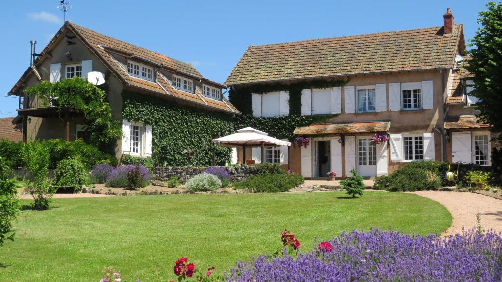 a house with a green yard with purple flowers at Le Serpolet in Ozolles