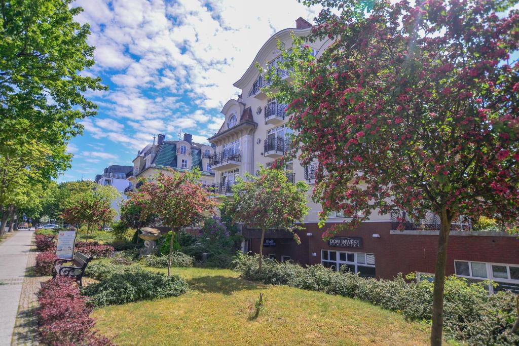 un edificio con un árbol delante de él en Apartamenty na Wyspie - Promenada, en Świnoujście