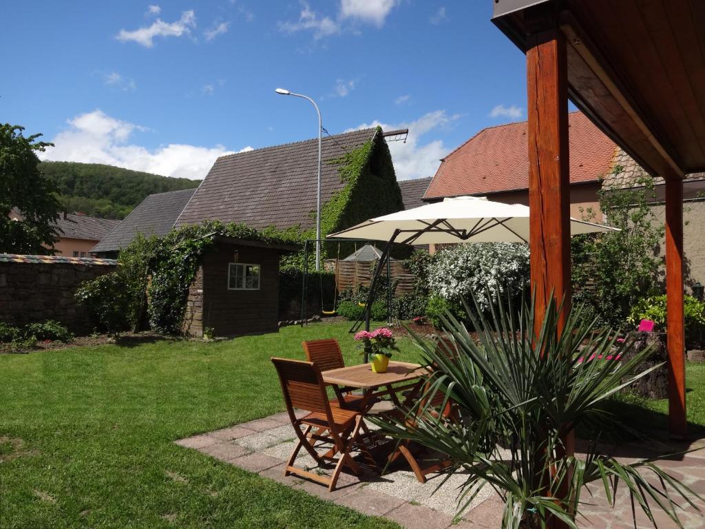 una mesa y sillas con una sombrilla en un patio en Un petit coin d’Alsace en Soultzmatt