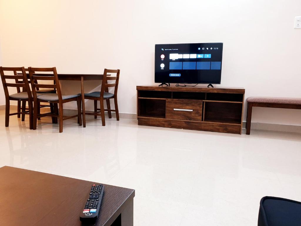 a living room with a tv and a table and chairs at Chippy Apartments No23 in Chennai