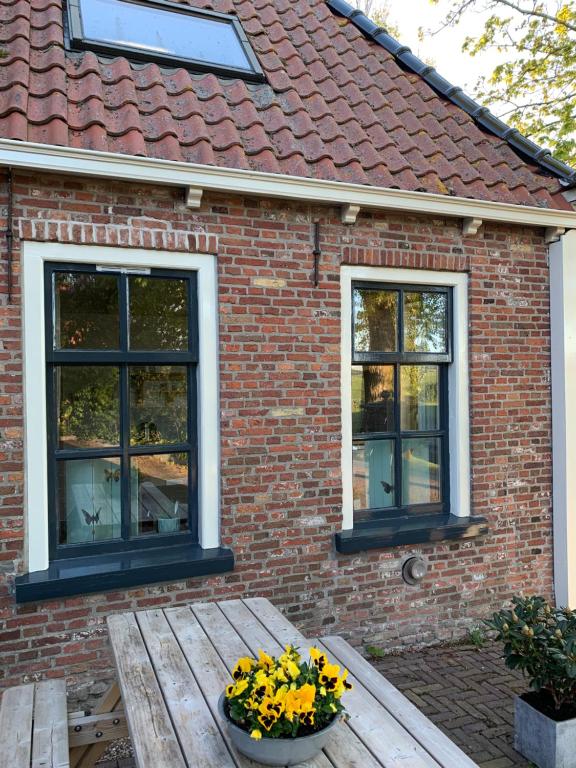 Casa con 2 ventanas y mesa de madera con flores en Logement Alde Leie, en Alde Leie