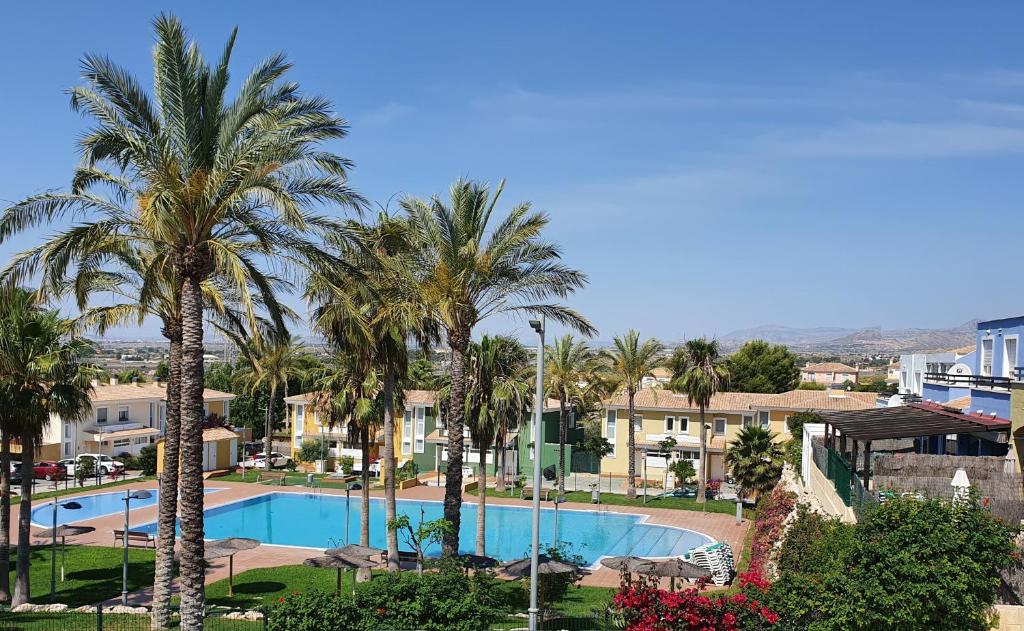 vistas a una piscina con palmeras y edificios en Chalet Bonalba Golf, en Alicante