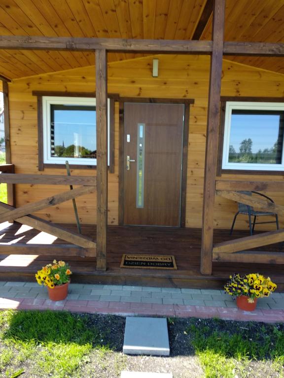 a wooden cabin with a wooden door and windows at Domki Orla in Pasym