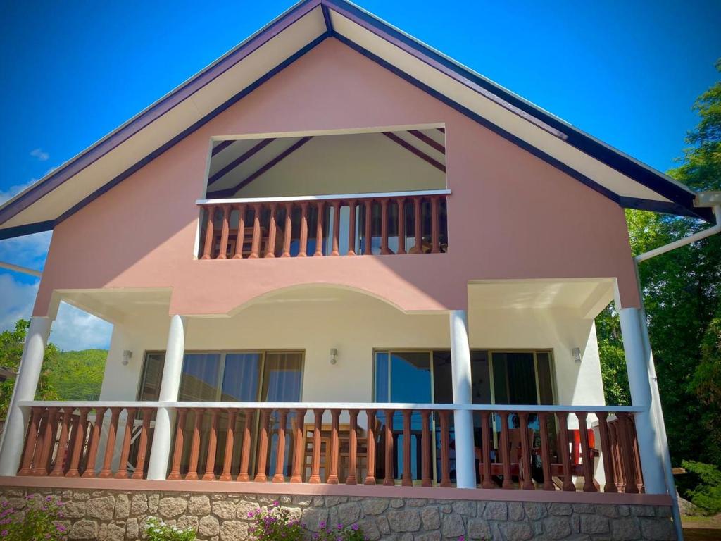 a pink house with a balcony at Vista D'Oro in Anse Possession