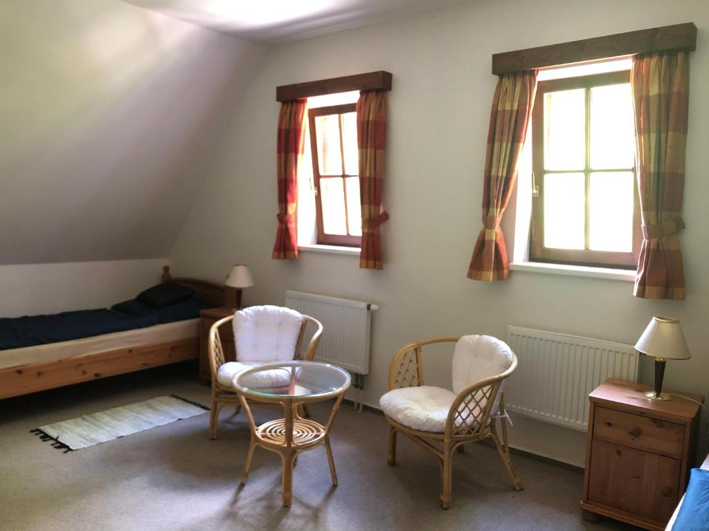 a bedroom with a bed and two chairs and a table at Malá Svatá Hora - penzion & restaurace in Mníšek pod Brdy