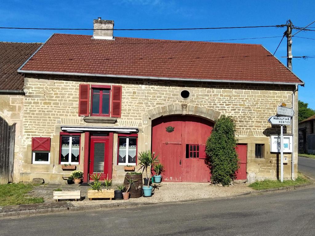 um edifício de tijolos com uma porta vermelha e janelas vermelhas em Au grain de Celles em Celles-en-Bassigny