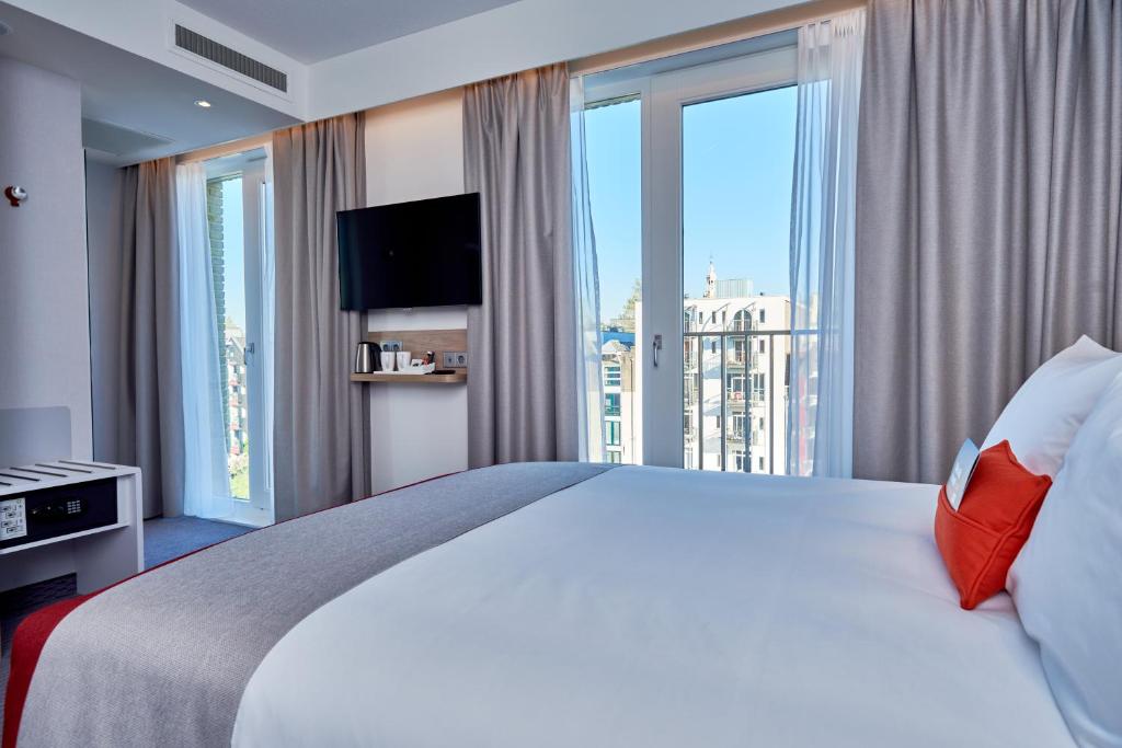 een hotelkamer met een groot bed en een groot raam bij Holiday Inn Express Amsterdam - City Hall, an IHG Hotel in Amsterdam