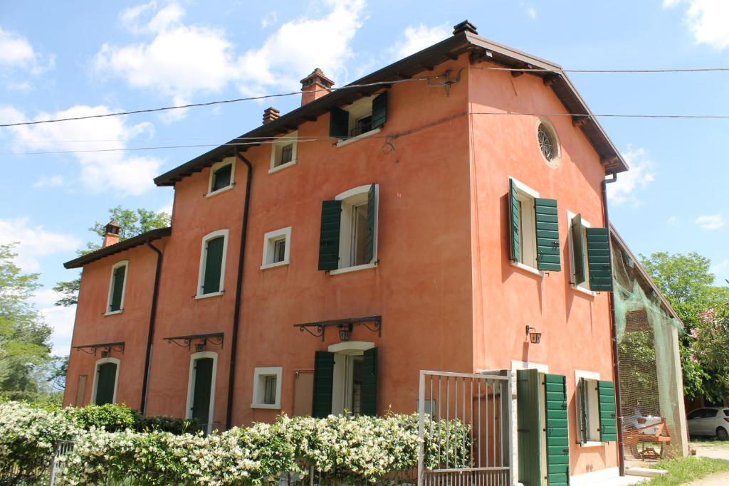 un antiguo edificio de ladrillo rojo con persianas verdes en CasaBencio, en Lazise