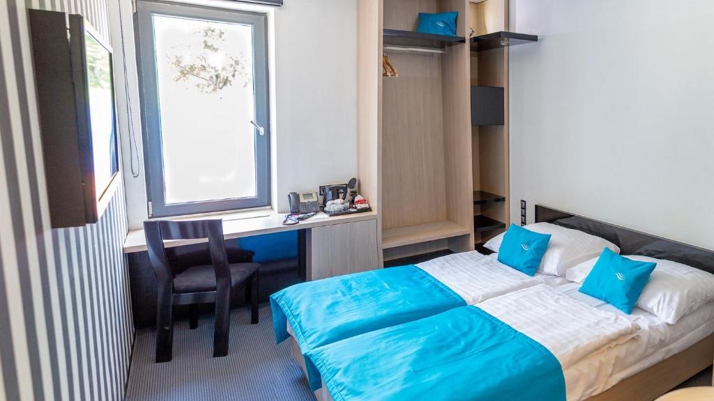 Schlafzimmer mit einem Bett, einem Schreibtisch und einem Fenster in der Unterkunft Hotel AquaCity Riverside in Poprad