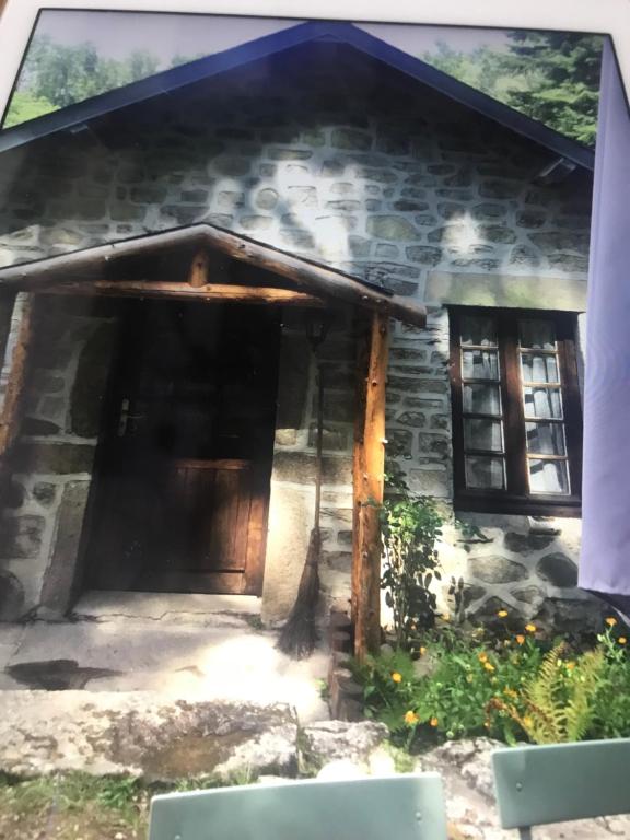 uma casa de pedra com uma porta e duas janelas em Woodland Cottage em Faux-la-Montagne
