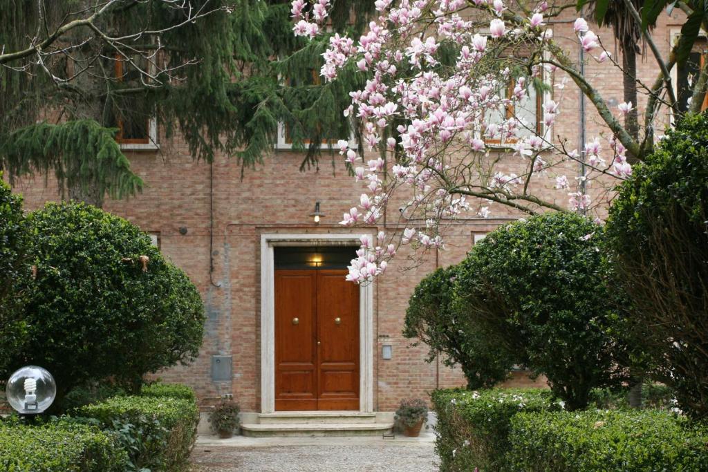 a brick building with a brown door and a tree with pink flowers at B&B La Coperta Ricamata in Siena
