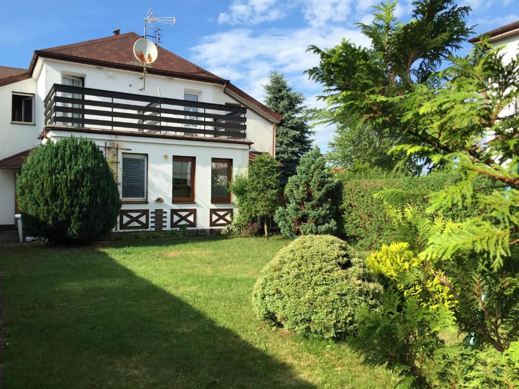 une maison blanche avec une cour entourée de buissons dans l'établissement Apartament Miriada 16, à Rowy