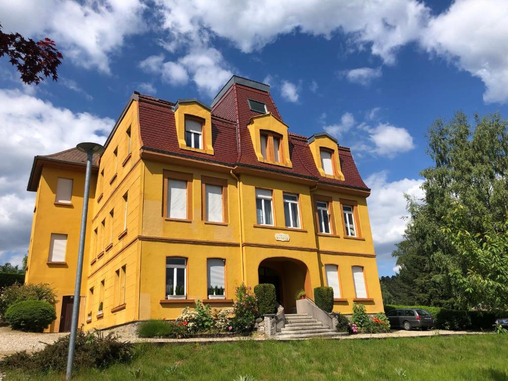 a yellow building with a red roof at Loft mon Soleil in Le Hohwald