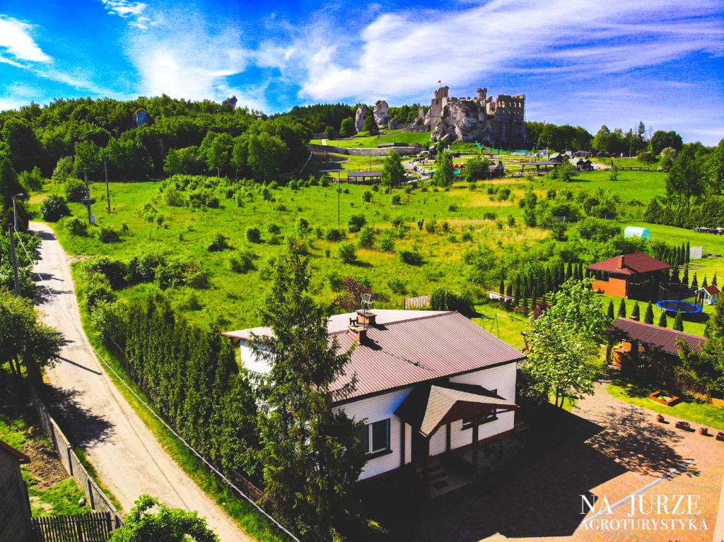 une maison dans un champ avec un château en arrière-plan dans l'établissement Agroturystyka na Jurze, à Ogrodzieniec