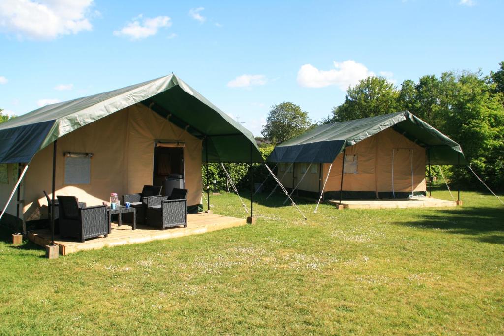 twee tenten met stoelen en een tafel in een veld bij Safaritent in Beilen