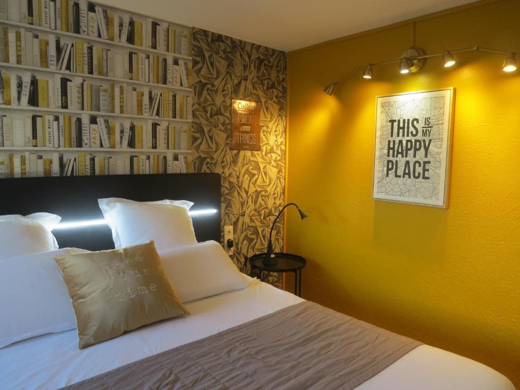 een slaapkamer met een bed met een gele muur bij Hôtel Kyriad Cap Sud in Avignon