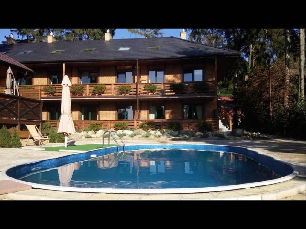 a large swimming pool in front of a house at Apartament Gaja in Poddąbie