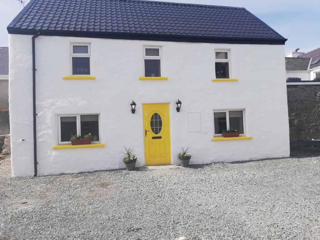 a white house with a yellow door and windows at The Barn @Ardhill House in Ardara